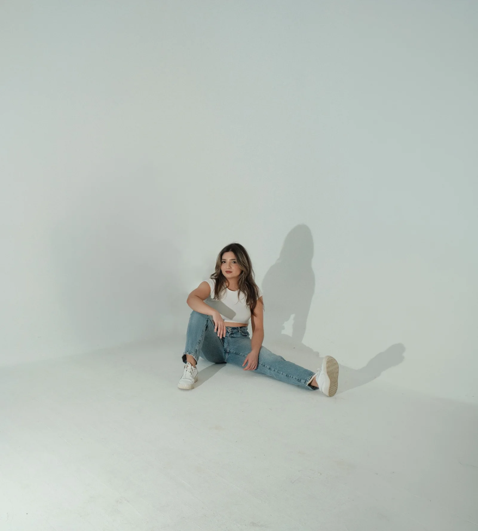 Laura Zuluaga sitting on the floor of a bright white studio